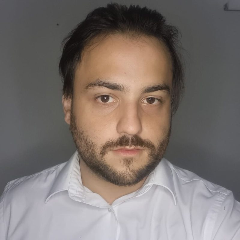 Foto do psicólogo João Gabriel de Campos Alves, especialista em Análise do Comportamento e Neuropsicologia na clínica Presente Psicologia. Ele veste uma camisa social branca, possui barba curta e transmite uma postura focada e acolhedora.